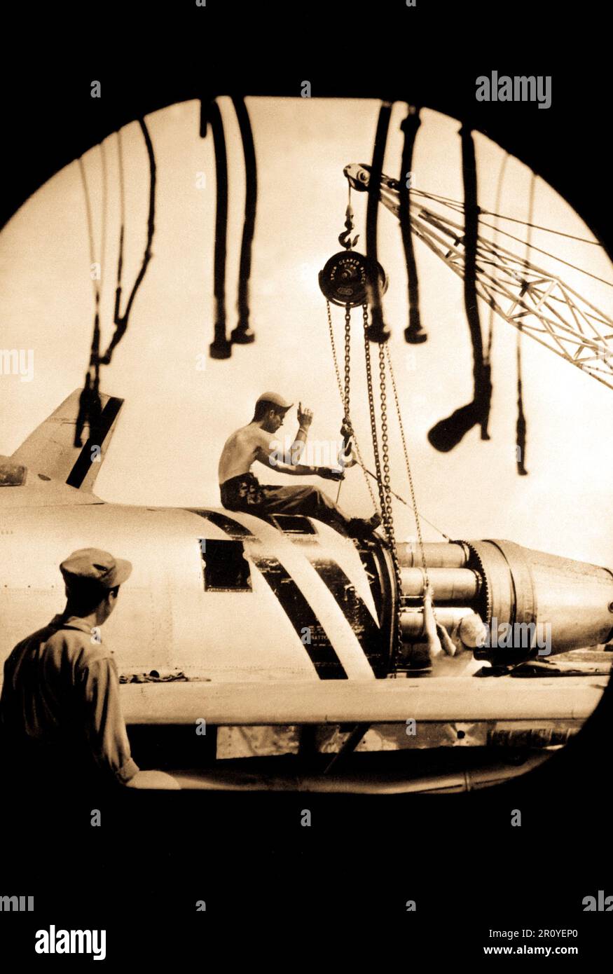 Une équipe de maintenance des aéronefs de l'US Air Forces canadiennes 4e Escadre Fighter-Interceptor en Corée, photographié par la tuyère d'échappement d'un F-86 Sabre, monte un moteur en place pour l'installation sur l'un des avions de combat à réaction. Septembre 1951. Banque D'Images