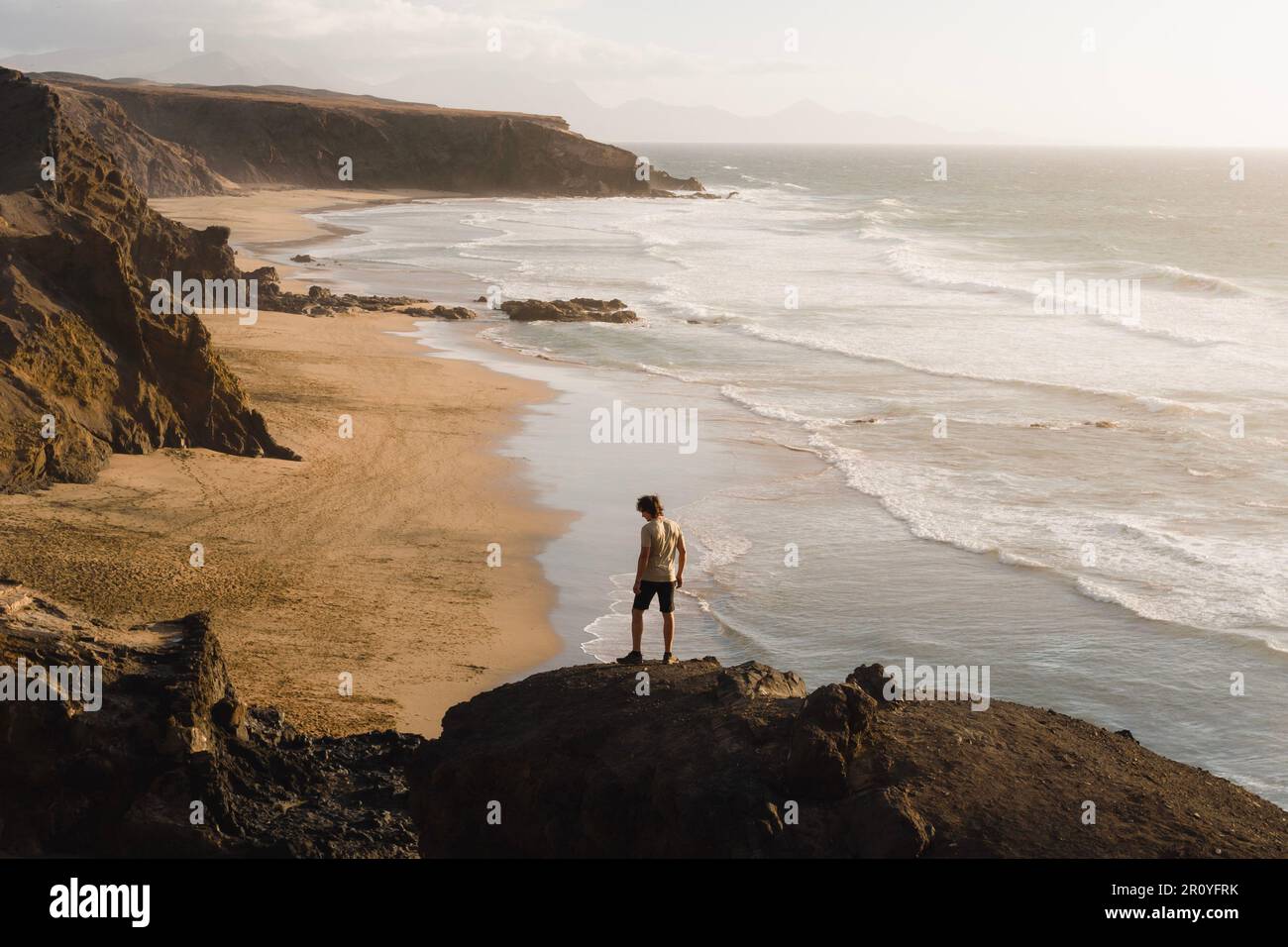 Le jeune homme profite du coucher du soleil sur la côte de Fuerteventura tout en faisant du tourisme dans les îles Canaries Banque D'Images