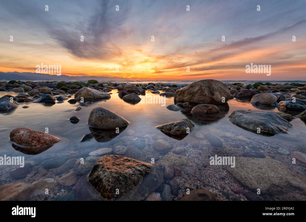 Un beau coucher de soleil sur l'océan avec Sea Rocks assis dans Une piscine de Tide haute résolution Banque D'Images