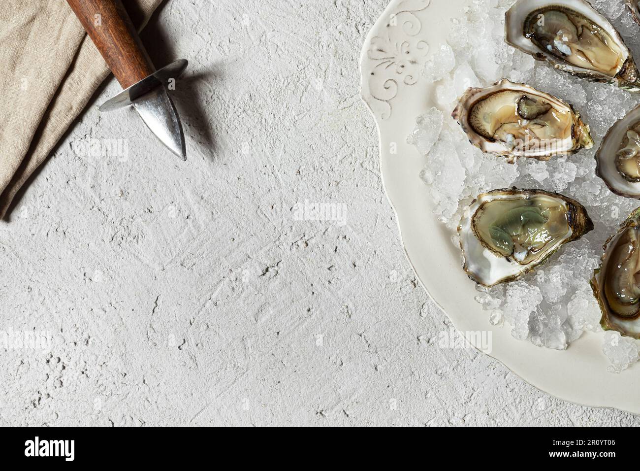 Assiette avec huîtres fraîches ouvertes et ouvre-huîtres sur table légère,  vue de dessus avec espace de copie Photo Stock - Alamy