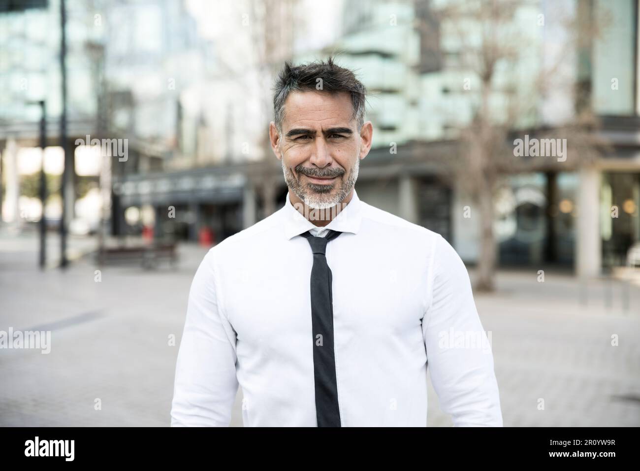 Portrait d'un beau PDG mûr souriant avec un fond urbain dans un style décontracté. Un homme d'affaires expérimenté et séduisant qui regarde la caméra avec confiance Banque D'Images