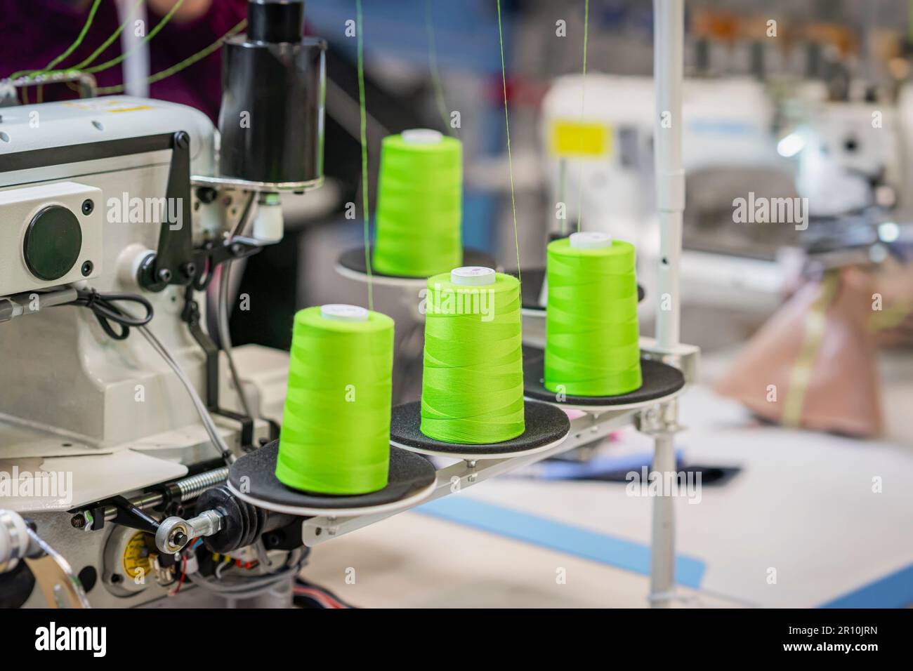 Bobines avec fils vert vif sur la machine à coudre de près. Équipement de couture, industrie textile et textile. Mise au point sélective Banque D'Images