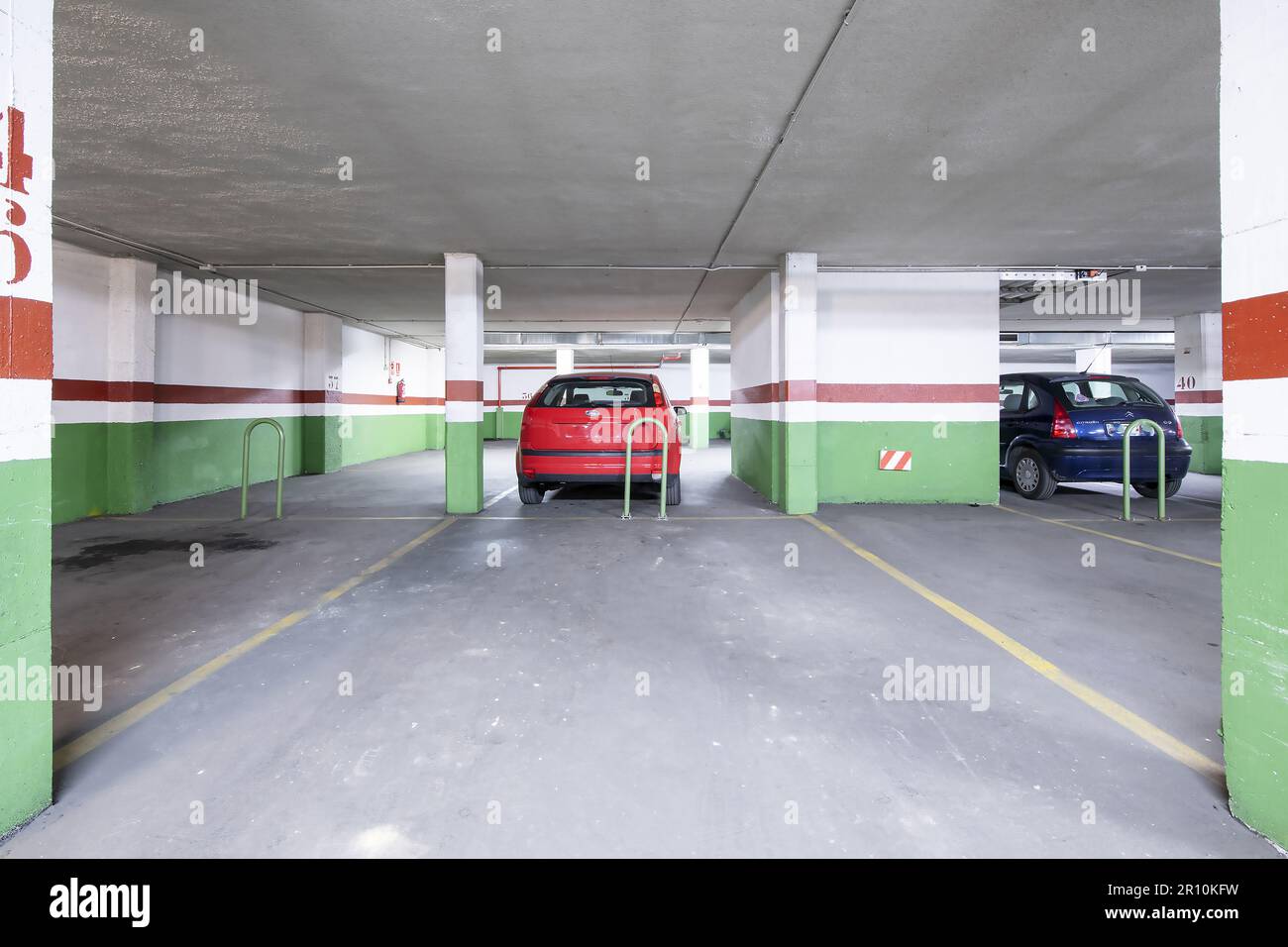 Quelques places de stationnement vides dans le sous-sol d'un immeuble résidentiel avec peinture rouge verte, lignes jaunes et planchers de ciment Banque D'Images