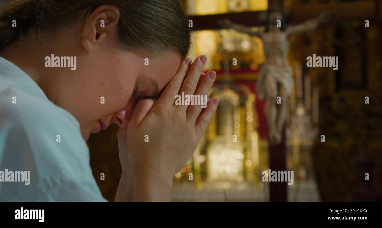 La femme a badié sa tête dans la prière à Dieu dans l'église. Les mains repliées dans la prière au Christ Rédempteur. Christianisme concept religieux. Vidéos cinématographiques en gros plan Banque D'Images