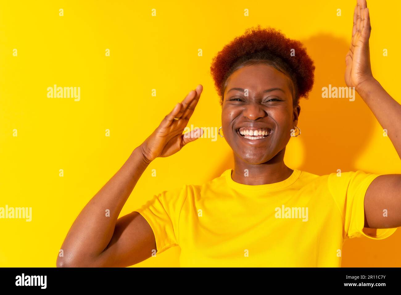 Jeune femme afro-américaine isolée sur fond jaune souriant et dansant, studio de tournage Banque D'Images