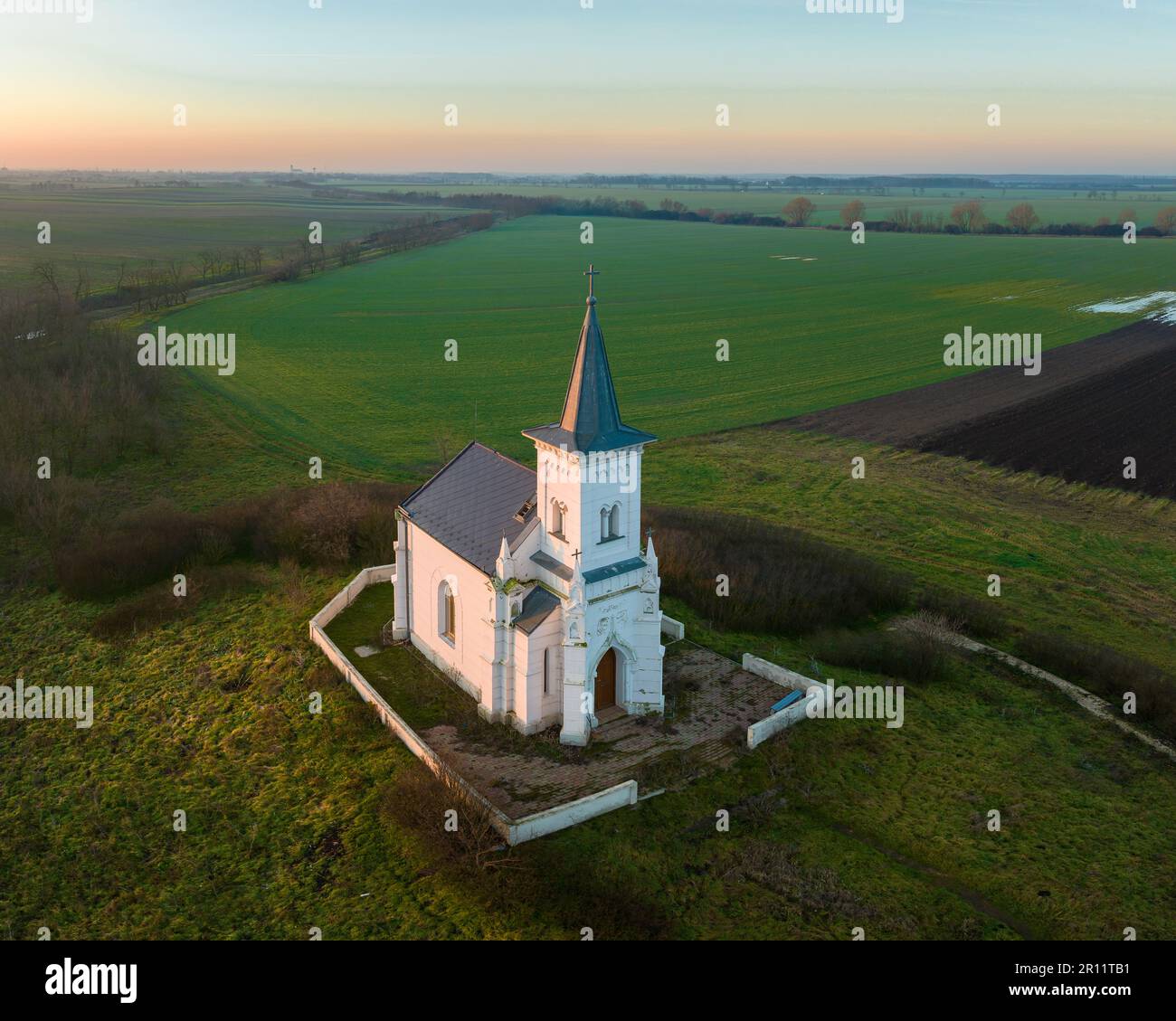 Petite chapelle blanche seule dans les chapes avec un ciel pittoresque de couleur lever de soleil. Le nom de la chapelle est Saint Chapelle Moritz dans le village d'Abadszalok en Hongrie. Banque D'Images