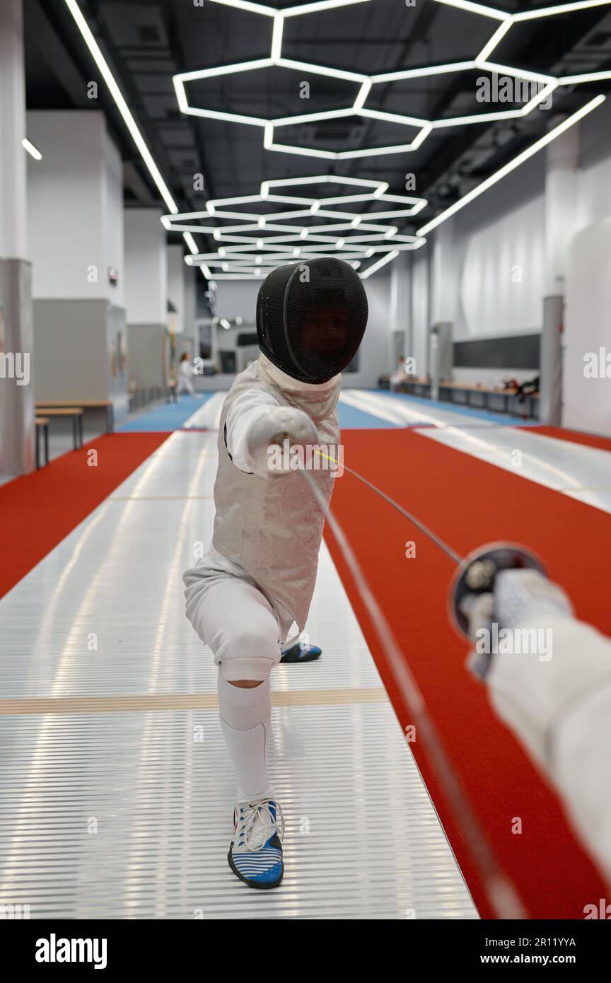 Swordsman debout dans la fente d'escrime pendant le combat d'entraînement dans le club de fencer Banque D'Images