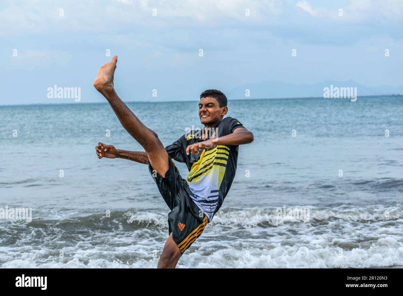 Un garçon bengali a fait un coup de pied à vélo sur l'eau de mer à la plage Banque D'Images