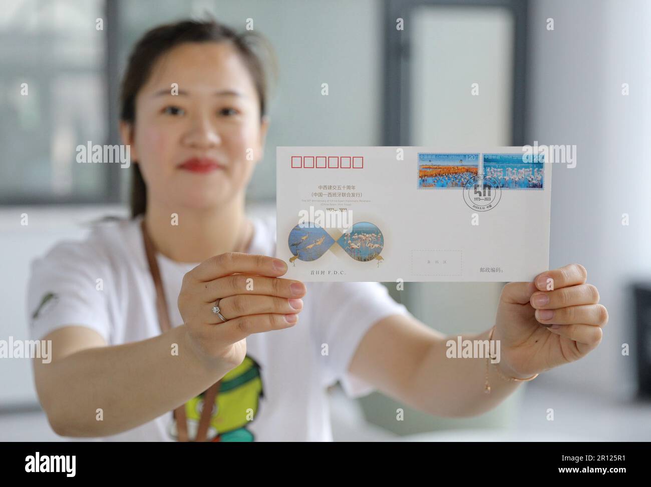 (230511) -- SHIJIAZHUANG, 11 mai 2023 (Xinhua) -- Un membre du personnel postal affiche une couverture du premier jour avec les timbres marquant le 50th anniversaire de l'établissement des relations diplomatiques entre la Chine et l'Espagne à Hengshui, dans la province de Hebei, au nord de la Chine, au 10 mai 2023. Une série de deux timbres a été émise mercredi pour marquer le 50th anniversaire de l'établissement des relations diplomatiques entre la Chine et l'Espagne. Les timbres, représentant la Laguna de Fuente de Piedra en Espagne et le lac Hengshui dans la province de Hebei au nord de la Chine, ont été conçus par le designer chinois de timbres Ma Lihang. Il est attendu que Banque D'Images