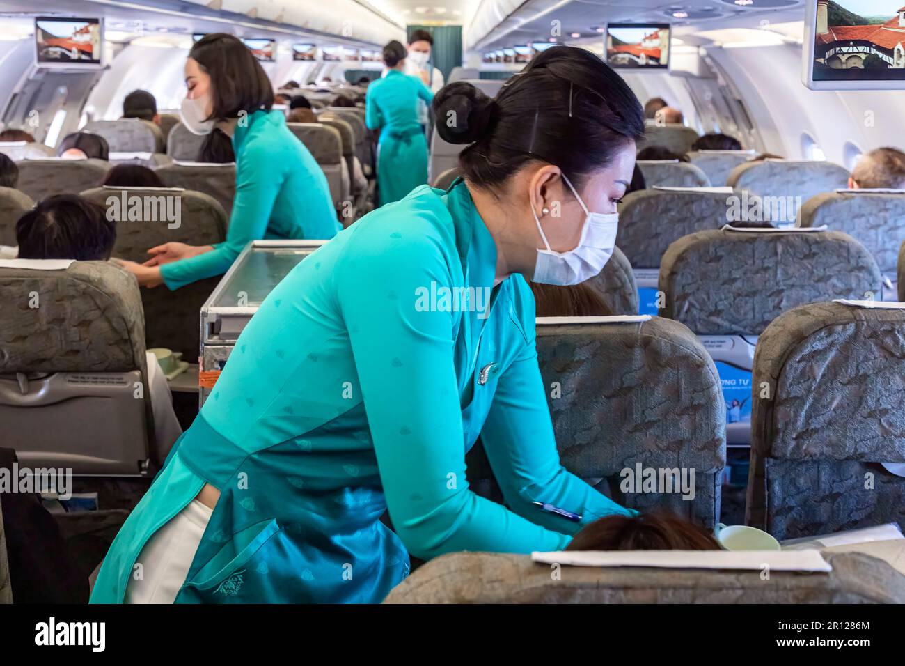 L'équipage de cabine de Vietnam Airlines porte l'uniforme AO dai traditionnel en vol Banque D'Images