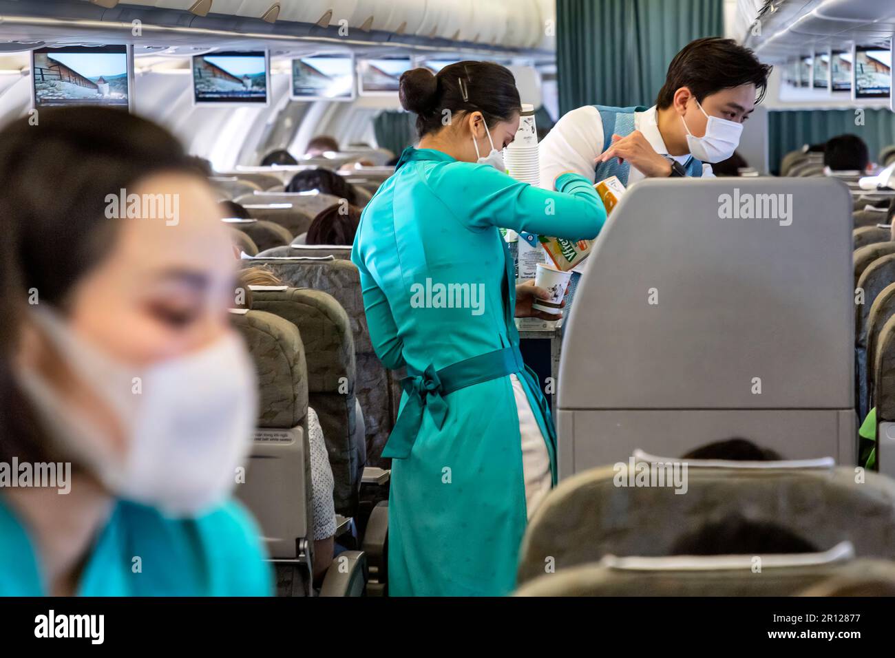 L'équipage de cabine de Vietnam Airlines porte l'uniforme AO dai traditionnel en vol Banque D'Images