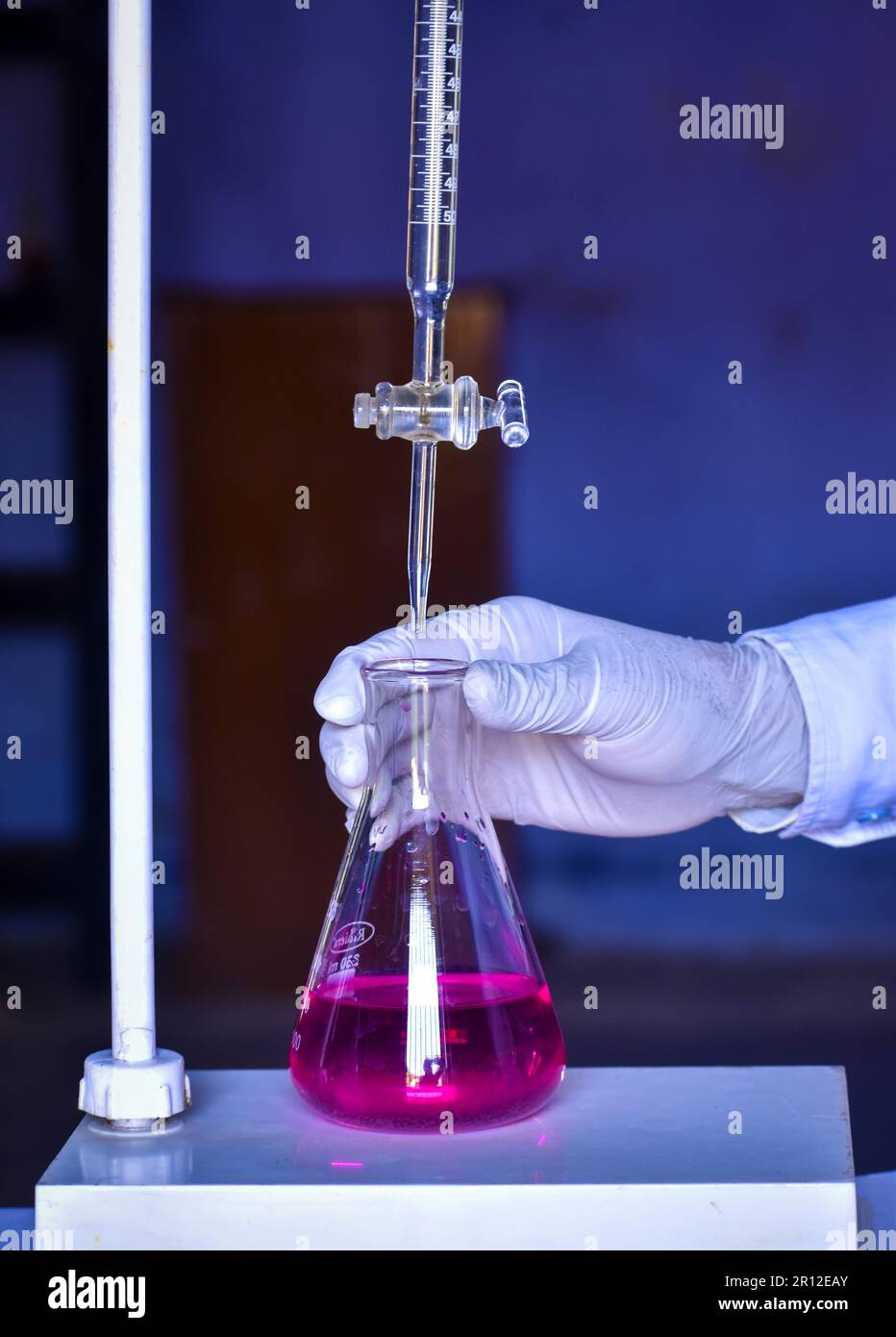L'étudiant effectue le titrage acido-basique, mesure et ajoute des solutions avec précision jusqu'à la neutralisation. Cette expérience aide à apprendre les chimis Banque D'Images