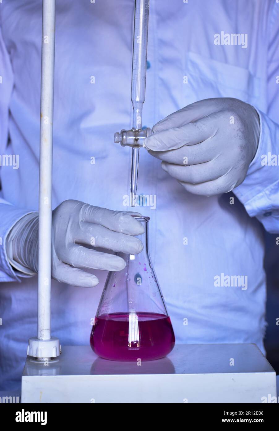 Le chimiste effectue un titrage acido-basique avec précision, en ajoutant des solutions jusqu'à la neutralisation. La précision des résultats est essentielle dans ce processus chimique. Banque D'Images