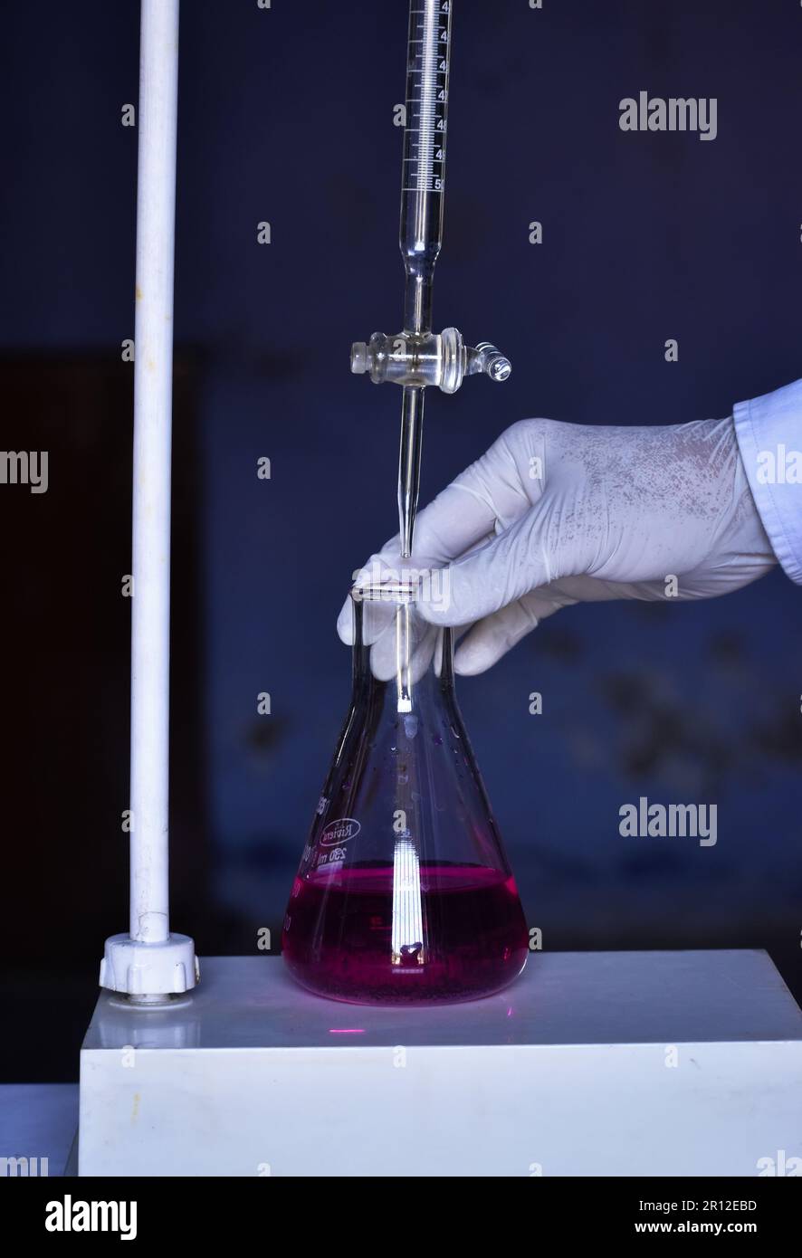 L'étudiant effectue le titrage acido-basique, mesure et ajoute des solutions avec précision jusqu'à la neutralisation. Cette expérience aide à apprendre les chimis Banque D'Images