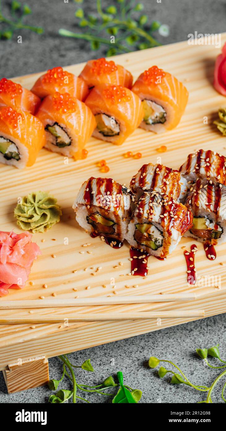 Image d'une variété de sushis japonais, y compris le maki, le sashimi et le concombre, disposés avec art sur un plateau en bois Banque D'Images