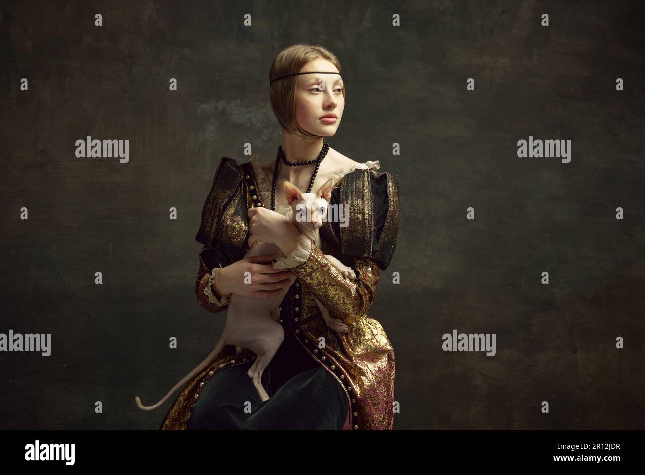 Portrait de la belle jeune fille dans des vêtements élégants sur fond sombre vintage posant avec chat sphynx. Dame avec réfabriquer de l'hermine Banque D'Images