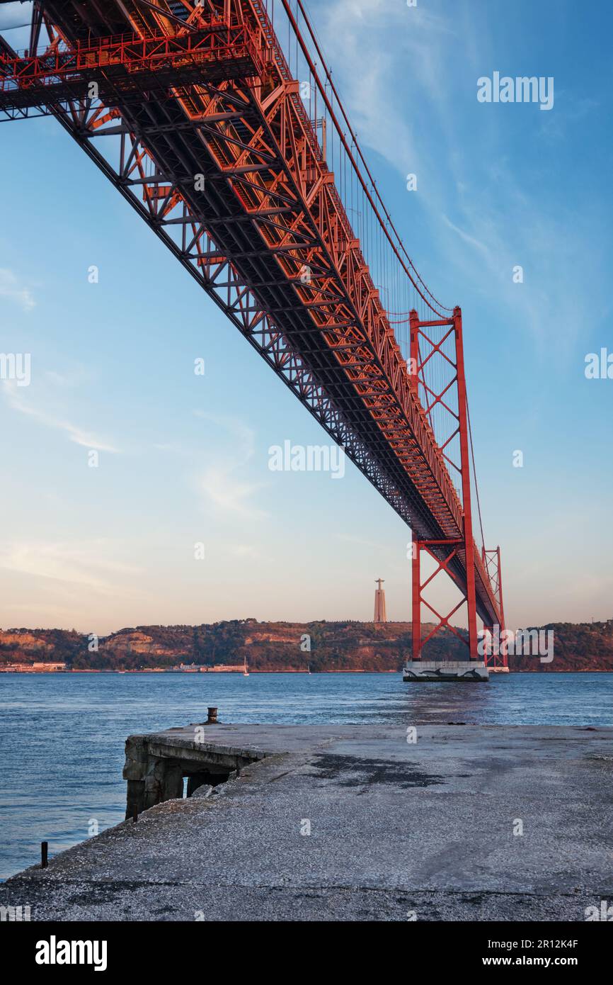 Vue sur le pont 25 de Abril au-dessus du Tage, le monument Christ le Roi et un quai. Lisbonne, Portugal Banque D'Images