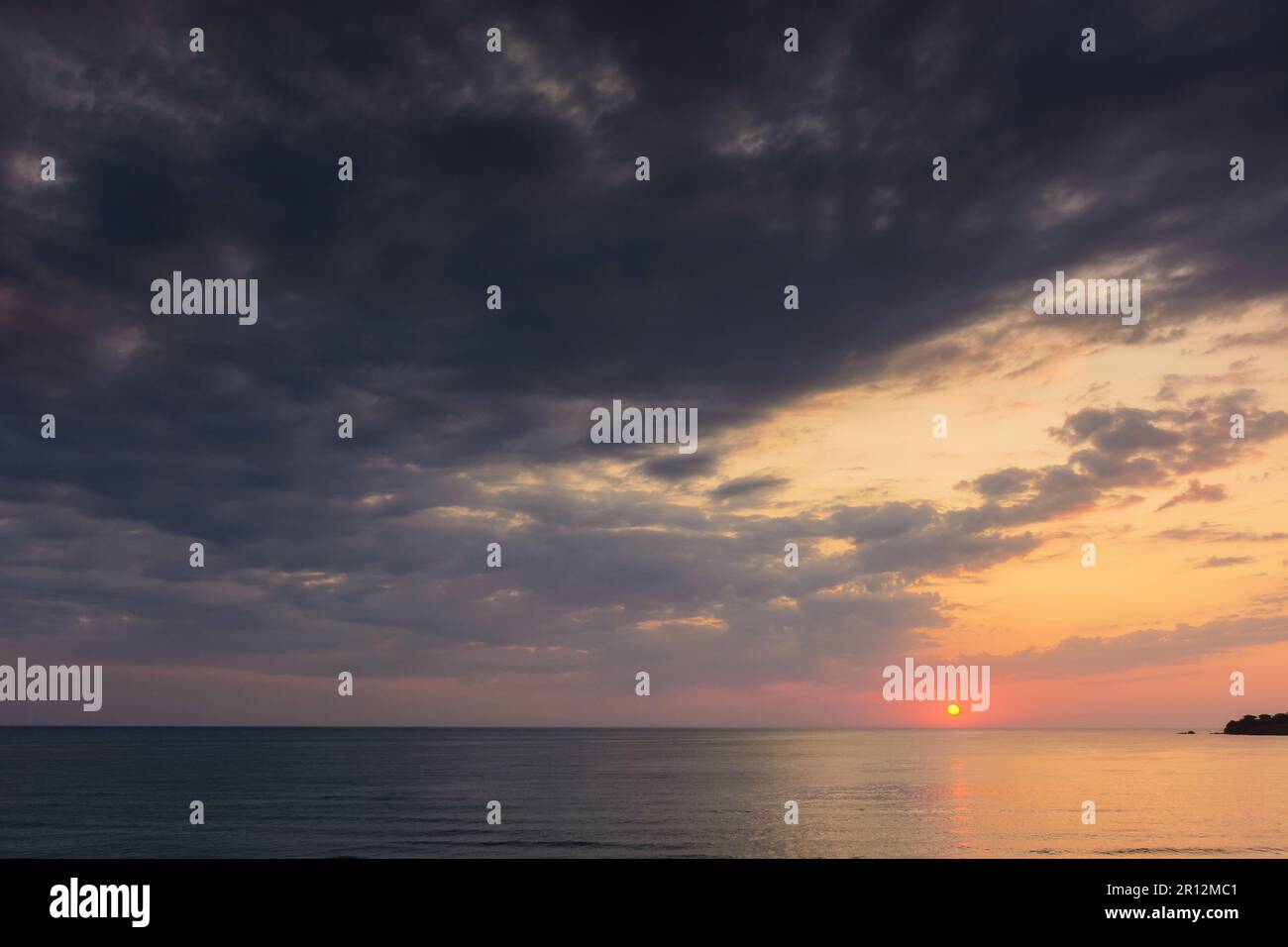 aube spectaculaire en mer. nuages gris sur le ciel avec soleil rouge au-dessus de l'horizon. vacances d'été météo pluvieuse Banque D'Images