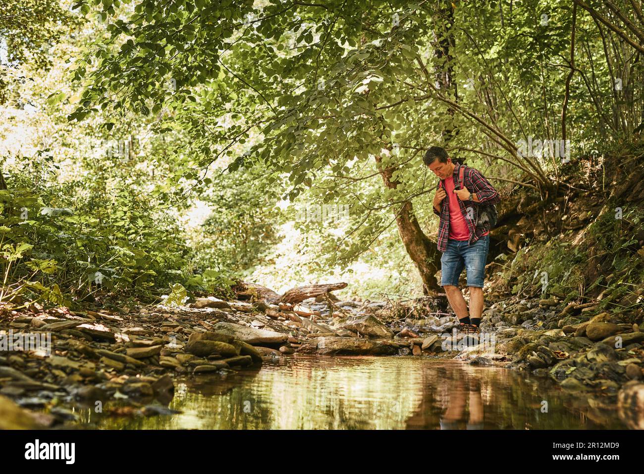 Trekking avec l'image concept de sac à dos. Backpacker en trekking bottes traversant la rivière de montagne. Homme randonnée dans les montagnes pendant le voyage d'été. Vacances Banque D'Images