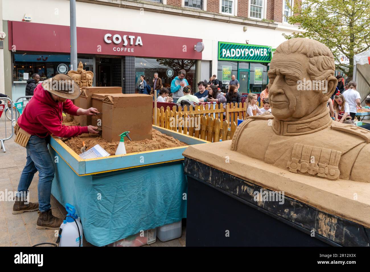 L'art du sable du roi Charles III dans le centre-ville de Kingston sur Hull, au Royaume-Uni, lors de son couronnement avec l'artiste vu sculpter derrière. Banque D'Images