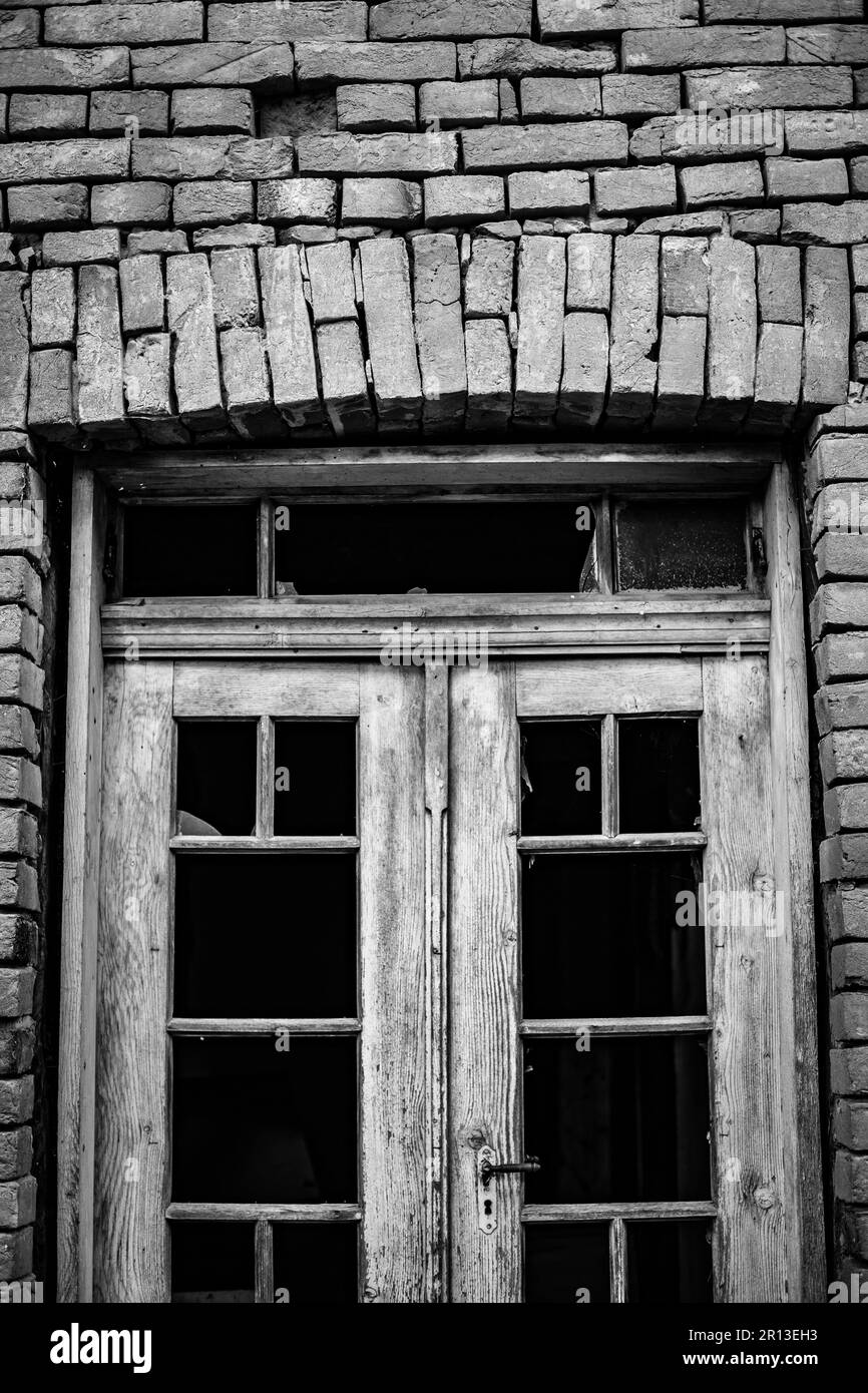 Photo de rue monochrome noir et blanc d'une ancienne porte de verre cassée en bois du bâtiment abandonné. Arche en briques au-dessus de l'entrée. Bulgarie, Europe Banque D'Images