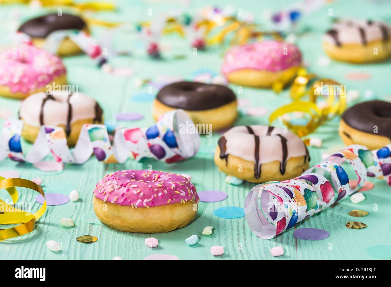 Beignets, berliner, Krapfen avec des banderoles et des confettis. Photo colorée de carnaval, d'anniversaire et de fête, fond vert Banque D'Images