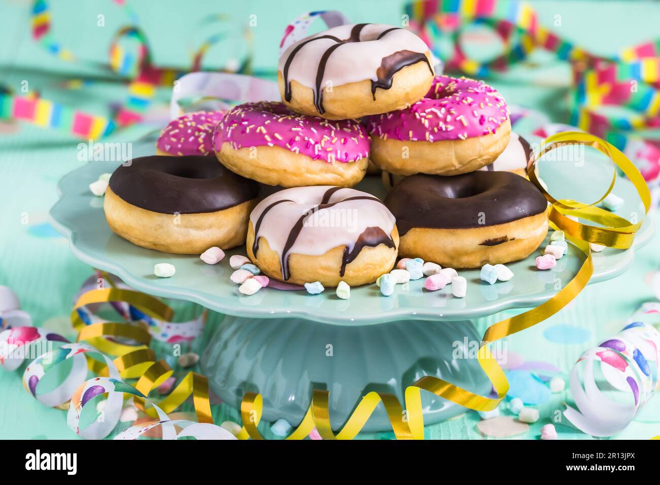 Beignets, berliner, Krapfen avec des banderoles et des confettis. Photo colorée de carnaval, d'anniversaire et de fête, fond vert Banque D'Images