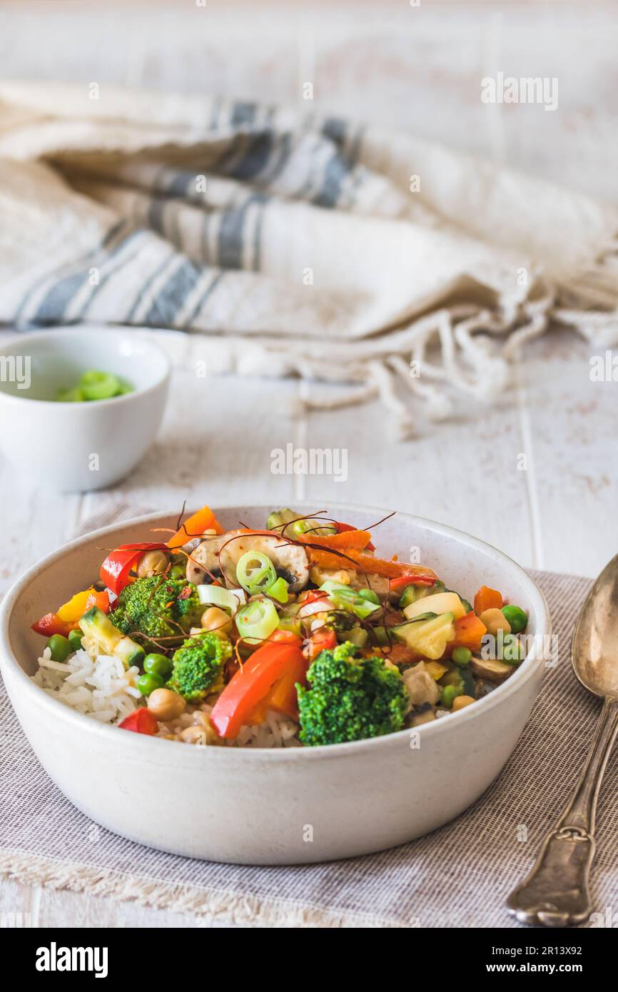 Bol avec riz et légumes sur table en bois blanc, végétarien, végétalien, nourriture saine, vertical Banque D'Images