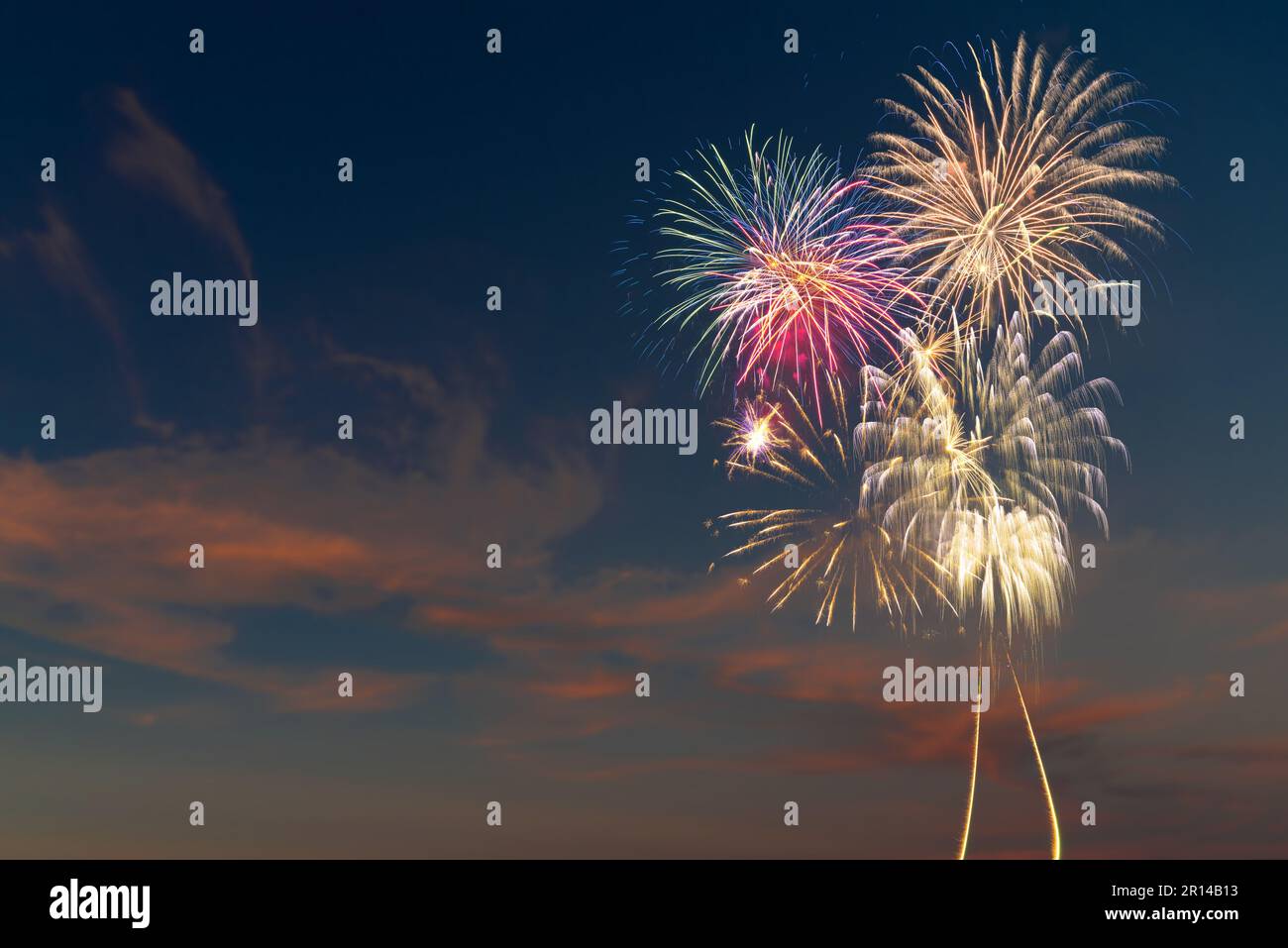 Feux d'artifice lumineux et colorés explosant dans un ciel bleu foncé avec des nuages. Contexte pour les fêtes d'anniversaire, les grands événements et les fêtes comme le 4th juillet Banque D'Images