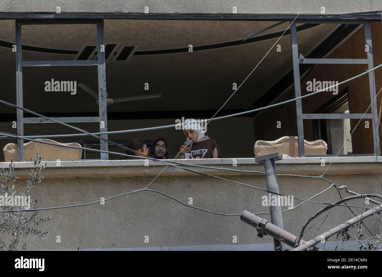 Gaza, Palestine. 11th mai 2023. Les Palestiniens regardent par la fenêtre de leur maison détruite près du domicile du membre du Jihad islamique, Aas al-Masri, après des frappes aériennes israéliennes dans la ville de Beit Lahiya, au nord de la bande de Gaza. Les militants palestiniens de Gaza ont tiré des roquettes vers Israël, après que l'armée israélienne ait mené une série de frappes aériennes sur des lance-roquettes du Jihad islamique. Crédit : SOPA Images Limited/Alamy Live News Banque D'Images