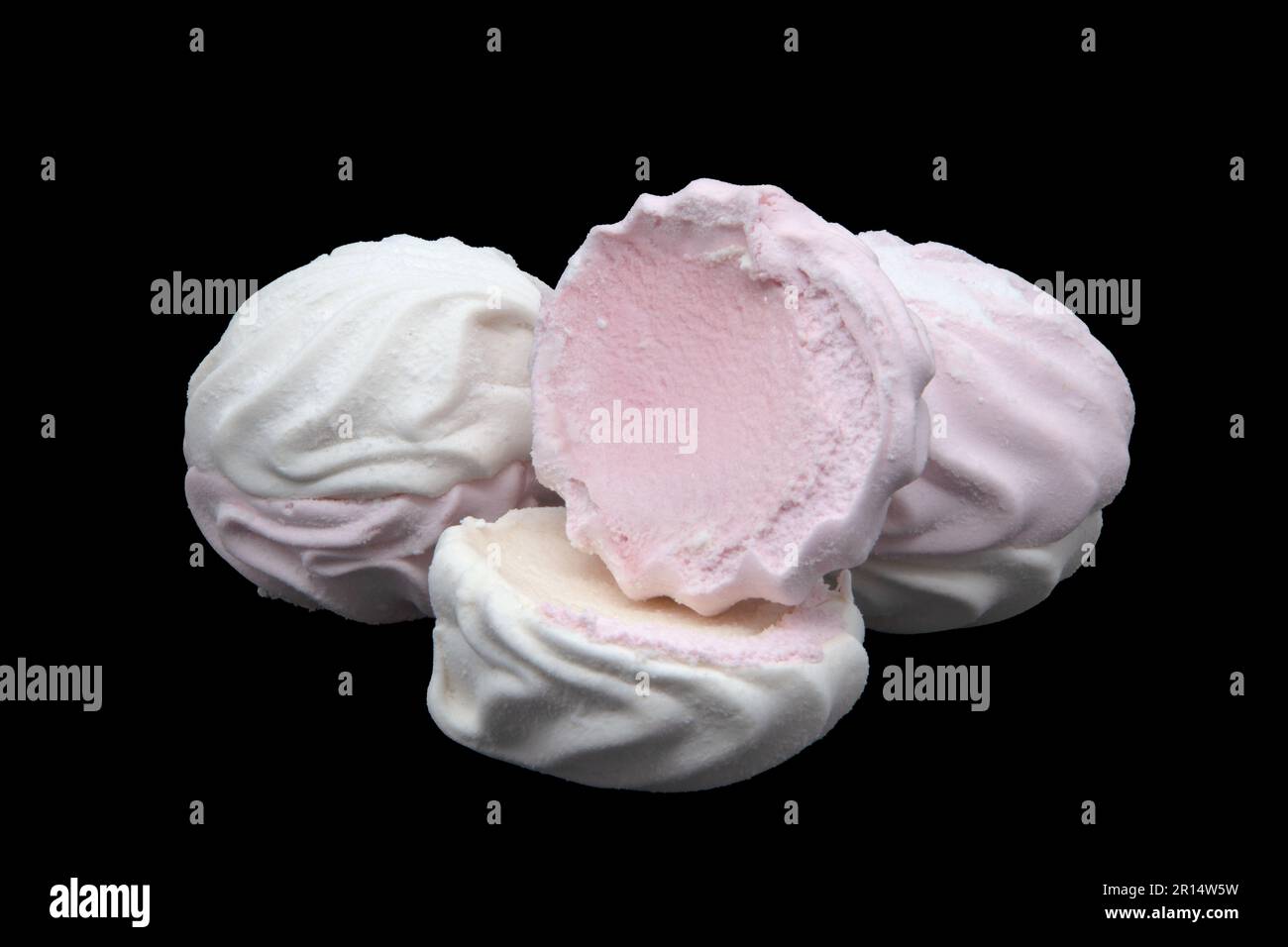 Guimauves à cannelures blanches et roses sur fond noir. Pièce entière et cassée. Photo du sujet. Photo de haute qualité. Horizontale Banque D'Images