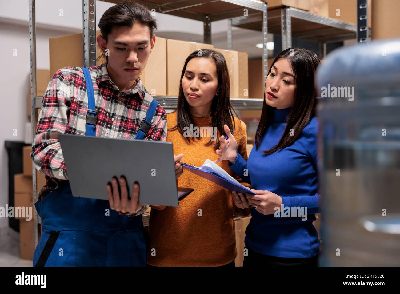Les employés de l'entrepôt gèrent les opérations de réception et d'envoi de colis en ligne sur ordinateur portable. L'équipe des responsables de magasin discute du rapport d'inventaire et travaille ensemble dans la salle de stockage Banque D'Images
