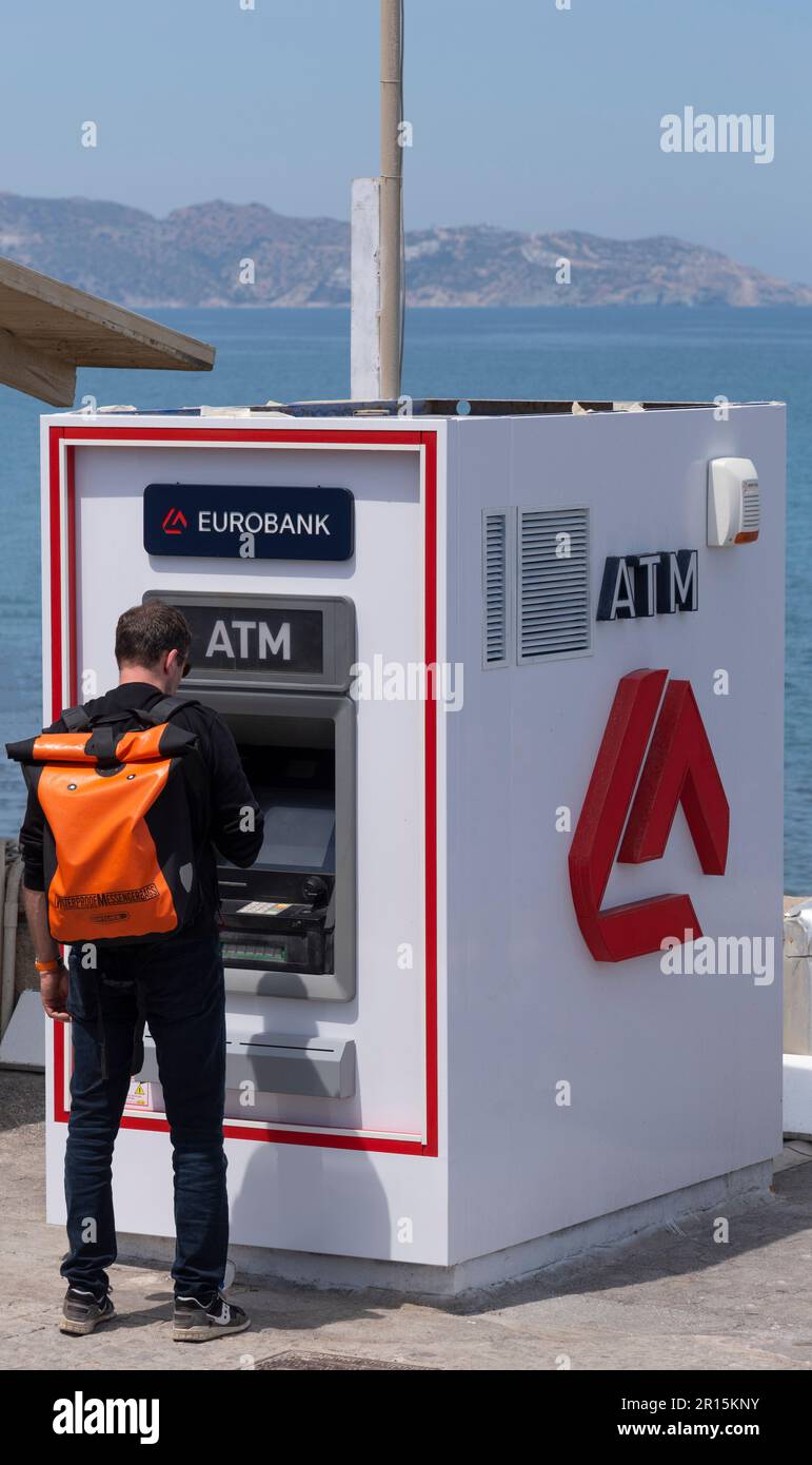 Crète, Grèce, UE. 2023. Homme dans la rue utilisant un distributeur de billets pour retirer des fonds, Banque D'Images