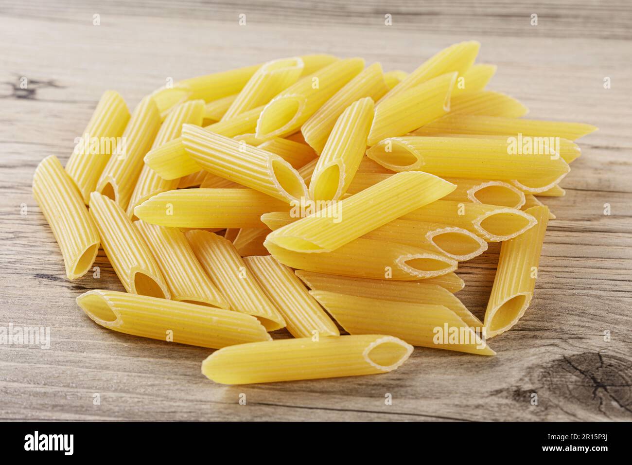 Nouilles de penne Rigate crues isolées sur fond de bois gris Banque D'Images