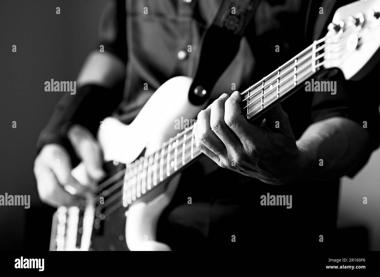 Les mains de l'homme sur les cordes d'une guitare basse avec une faible profondeur de champ Banque D'Images