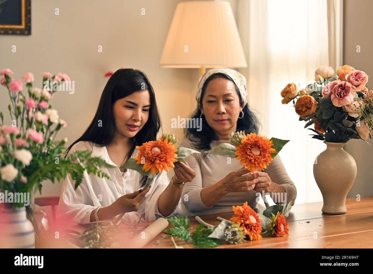 Jeune femme asiatique attrayante se joignant à l'atelier d'arrangement de fleurs fraîches avec sa mère. Concepts de loisirs et de temps familial Banque D'Images
