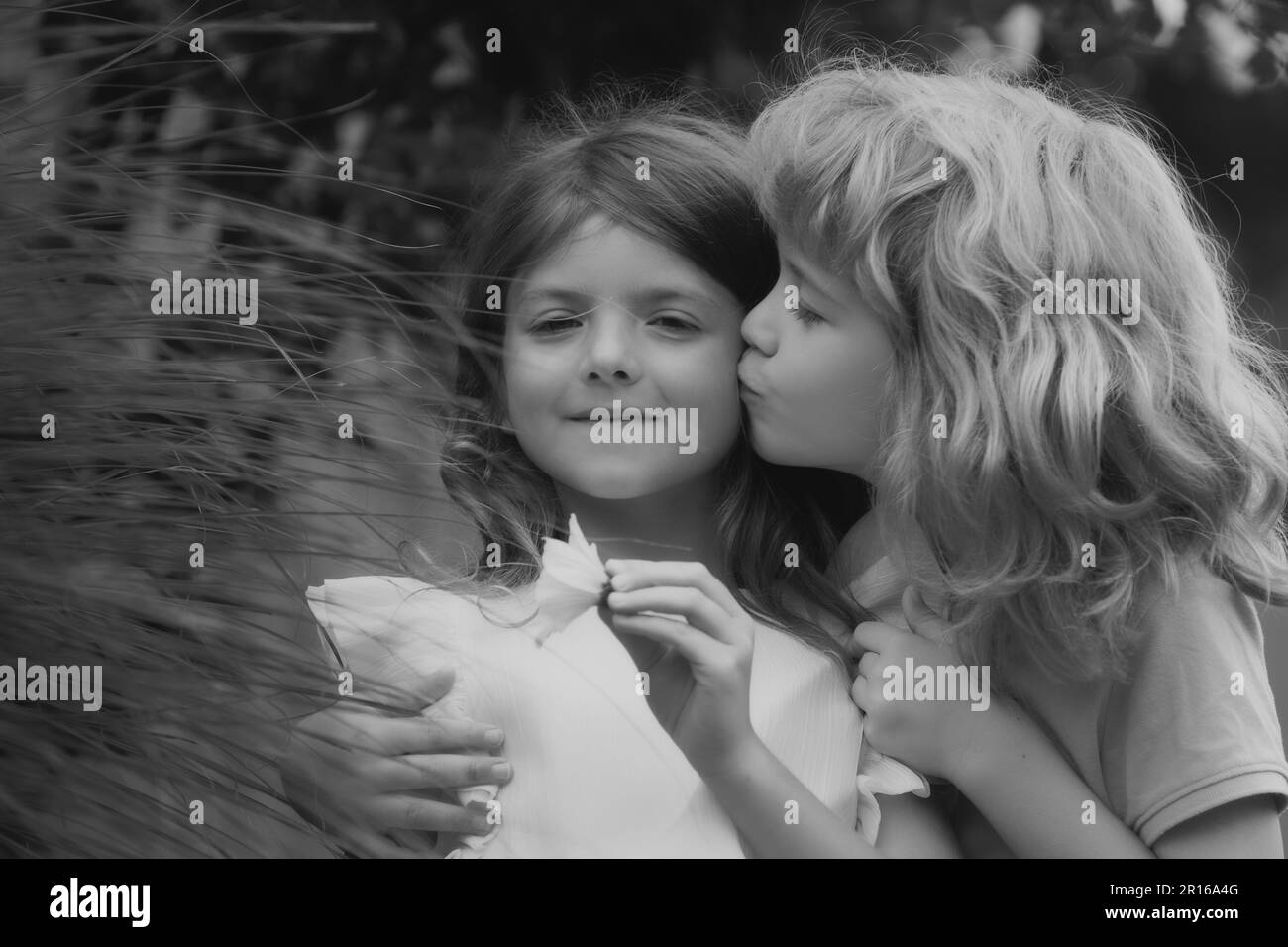 Couple d'enfants embrassant et embrassant. Petits enfants adorables à l'extérieur. Enfants dans le parc d'été, en gros plan. Les enfants aiment ensemble. Banque D'Images