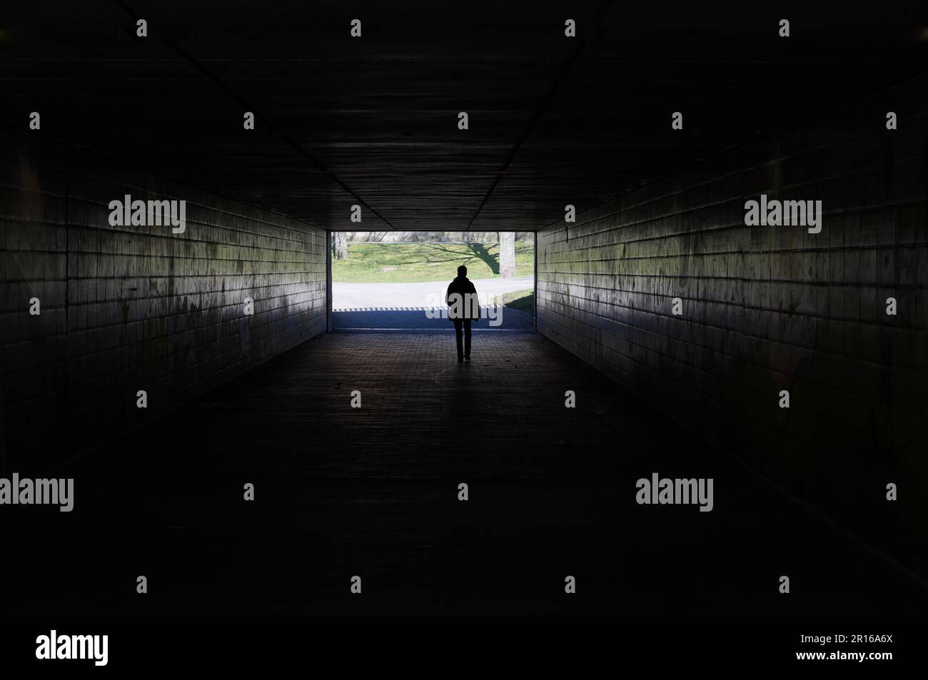 Silhouette d'une personne marchant à travers un tunnel sombre symbolisant la lumière au bout du tunnel Banque D'Images