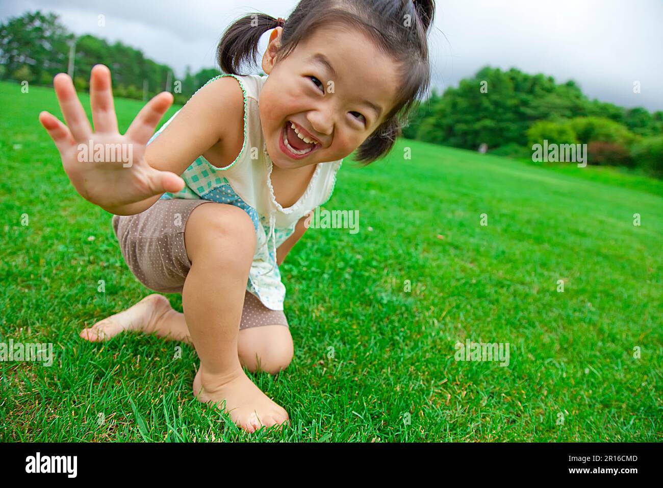 Fille jouant dans la pelouse du parc Banque D'Images