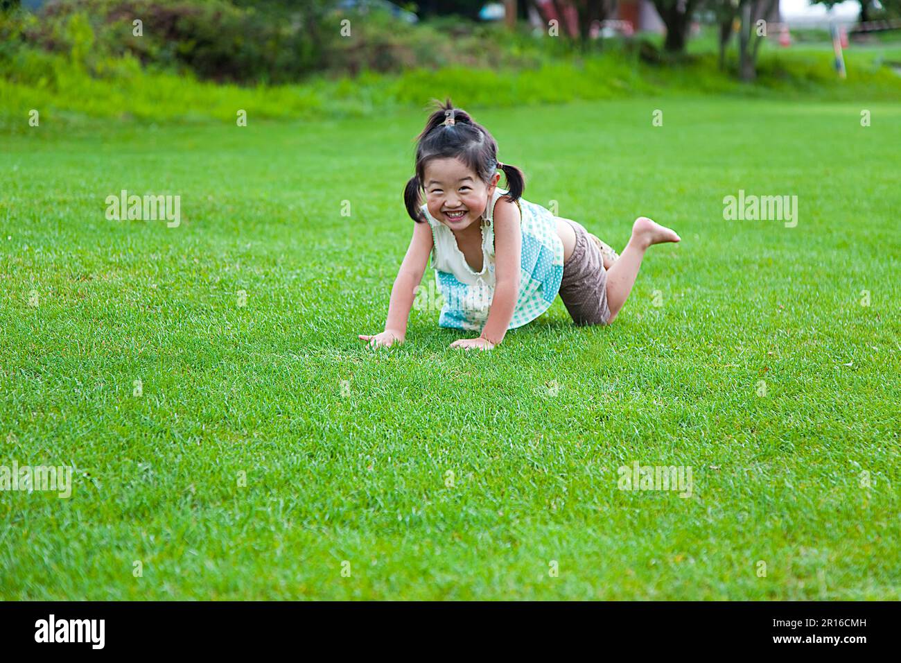Fille jouant dans la pelouse du parc Banque D'Images
