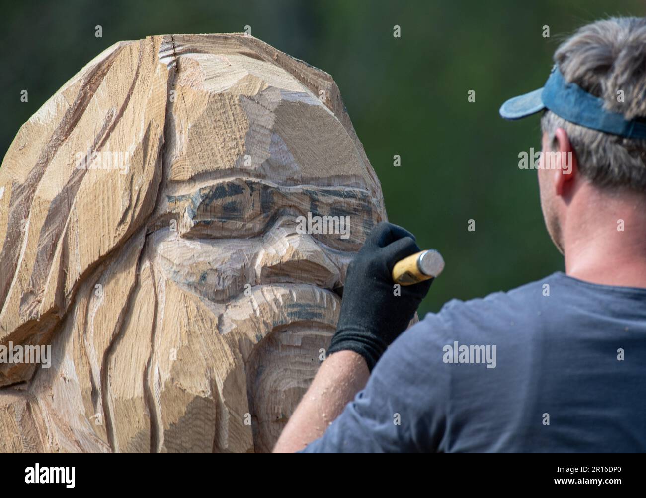 11 mai 2023, Mecklembourg-Poméranie occidentale, Zinnowitz: Tim Weigelt, sculpteur sur bois, réalise une sculpture en bois de Wolfgang Bordel, directeur du Vorpommersche Landesbühne, décédé l'automne dernier, au Symposium sur la sculpture sur bois de Zinnowitz. Une figure en bois de l'ancien homme de théâtre sera créée à partir d'un énorme tronc de chêne à l'aide d'une tronçonneuse, d'un marteau, d'un burin et d'autres outils. La sculpture doit ensuite être érigée à proximité immédiate de l'académie de théâtre de Zinnowitz, sur 29 juillet 2023. Des artistes de différents pays européens travailleront sur leurs sculptures en bois sous les yeux des spectateurs Banque D'Images