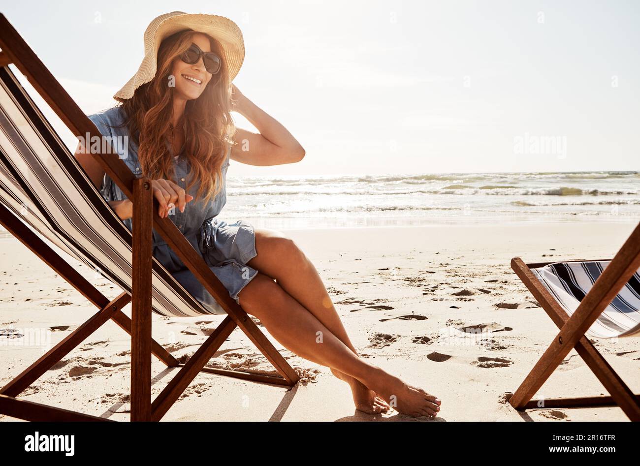 Il y a des tas de soleil pour s'y baigner. une jeune femme se détendant sur un transat à la plage. Banque D'Images