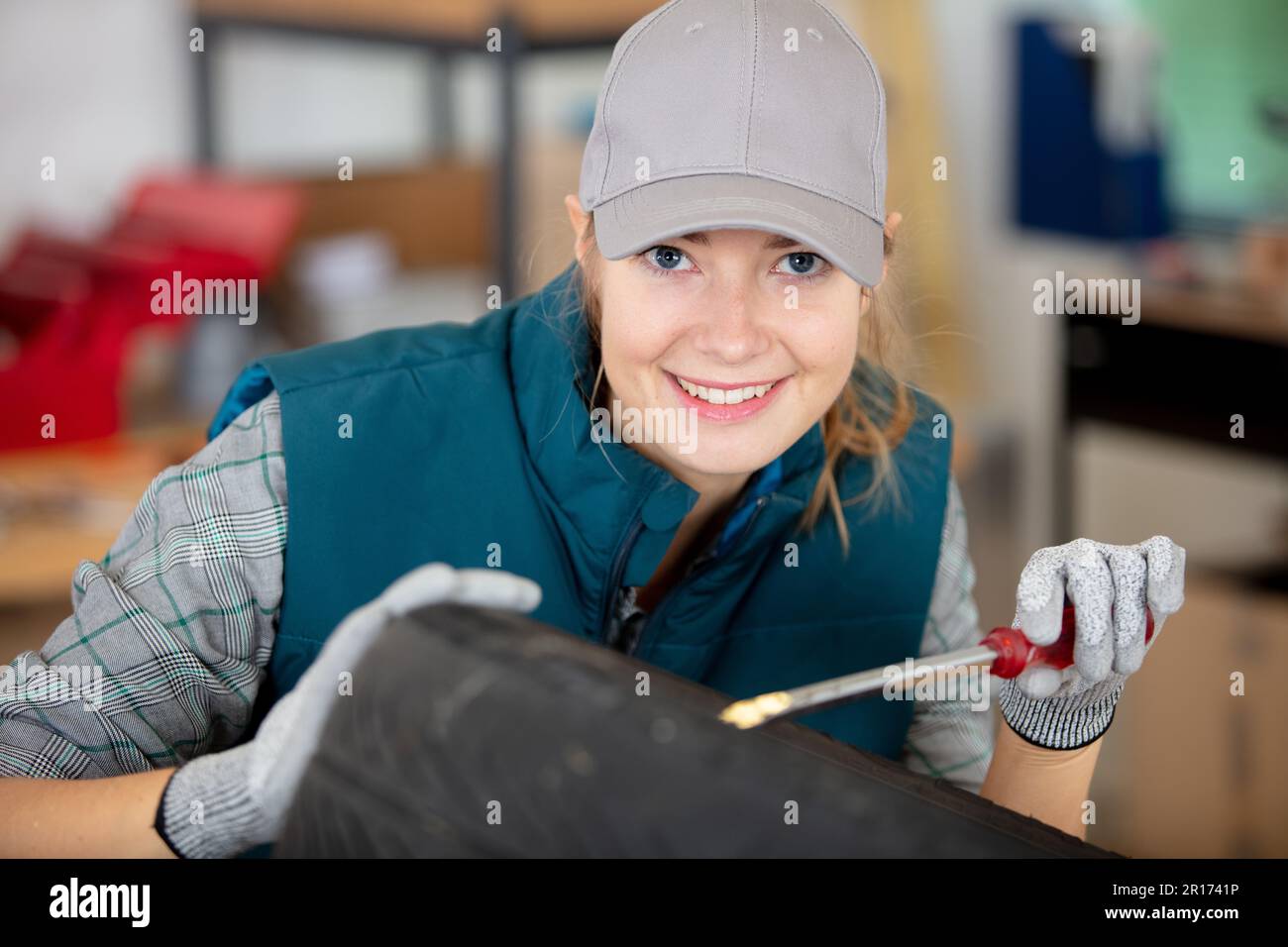 femme mécanicien travaillant sur les pièces à l'aide d'un tournevis dans l'atelier Banque D'Images