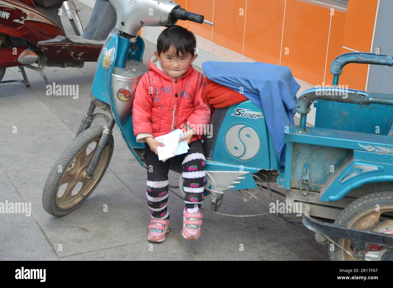 République populaire de Chine, Tibet, Tsetang: Un jeune tibétain qui garde le scooter de son père. Banque D'Images
