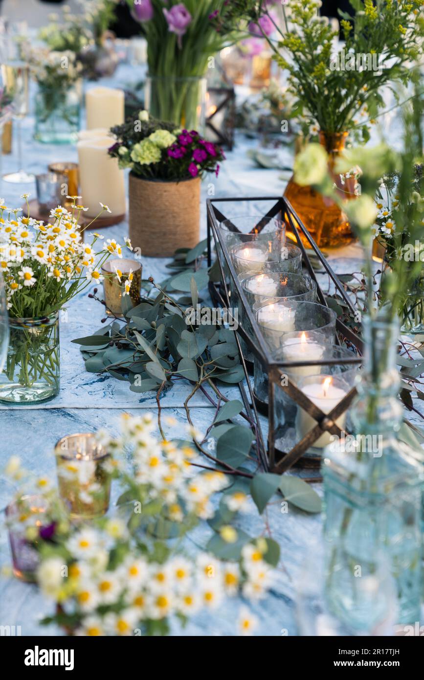 Disposition bougies et fleurs pour la mise en place d'une table de mariage Banque D'Images