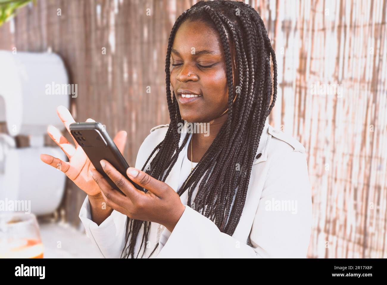 Femme afro-américaine utilisant un smartphone assis à l'extérieur Banque D'Images