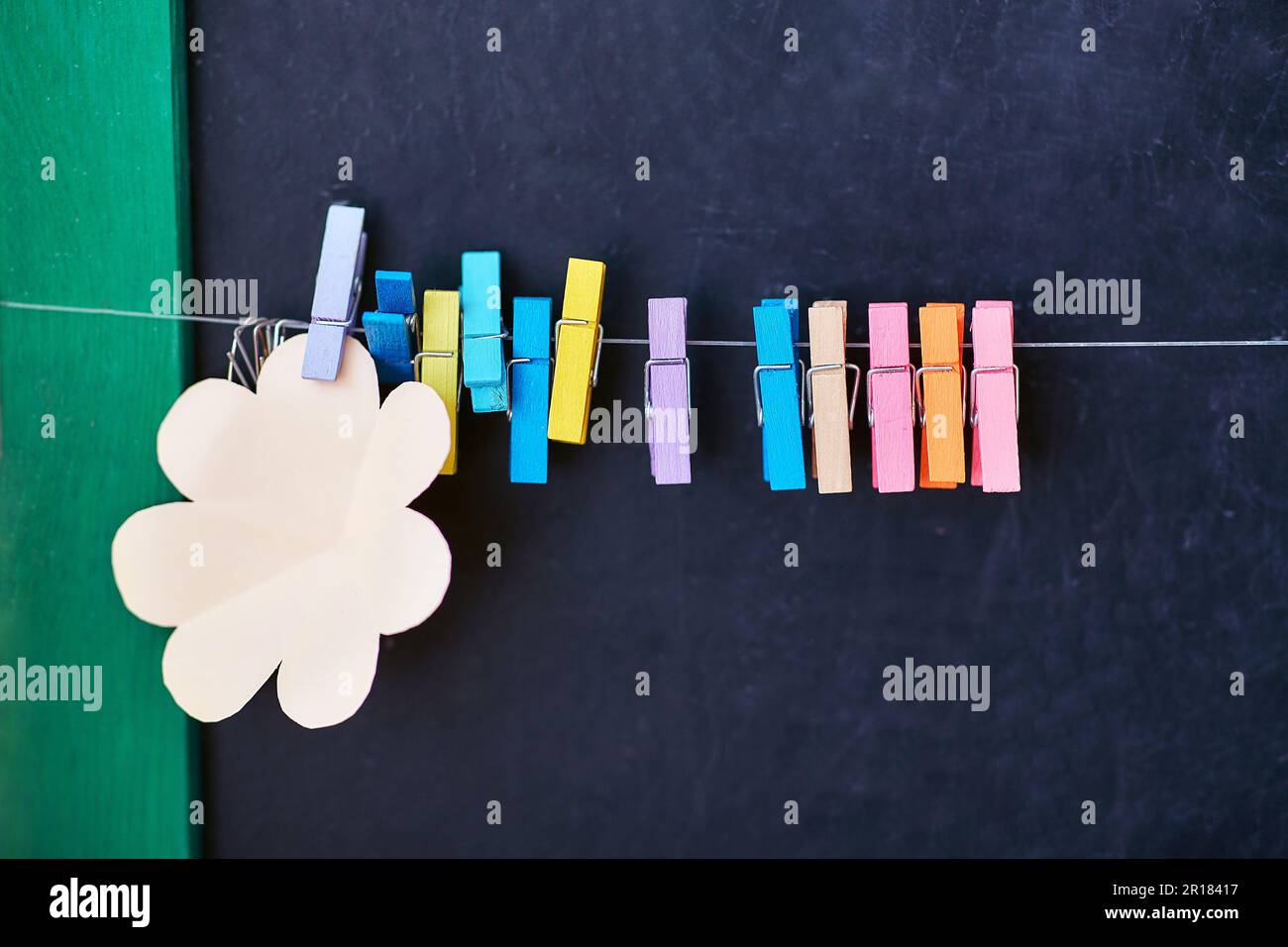 corde avec épingles à linge de couleur et autocollants vierges pour les notes sur fond noir de planche scolaire Banque D'Images