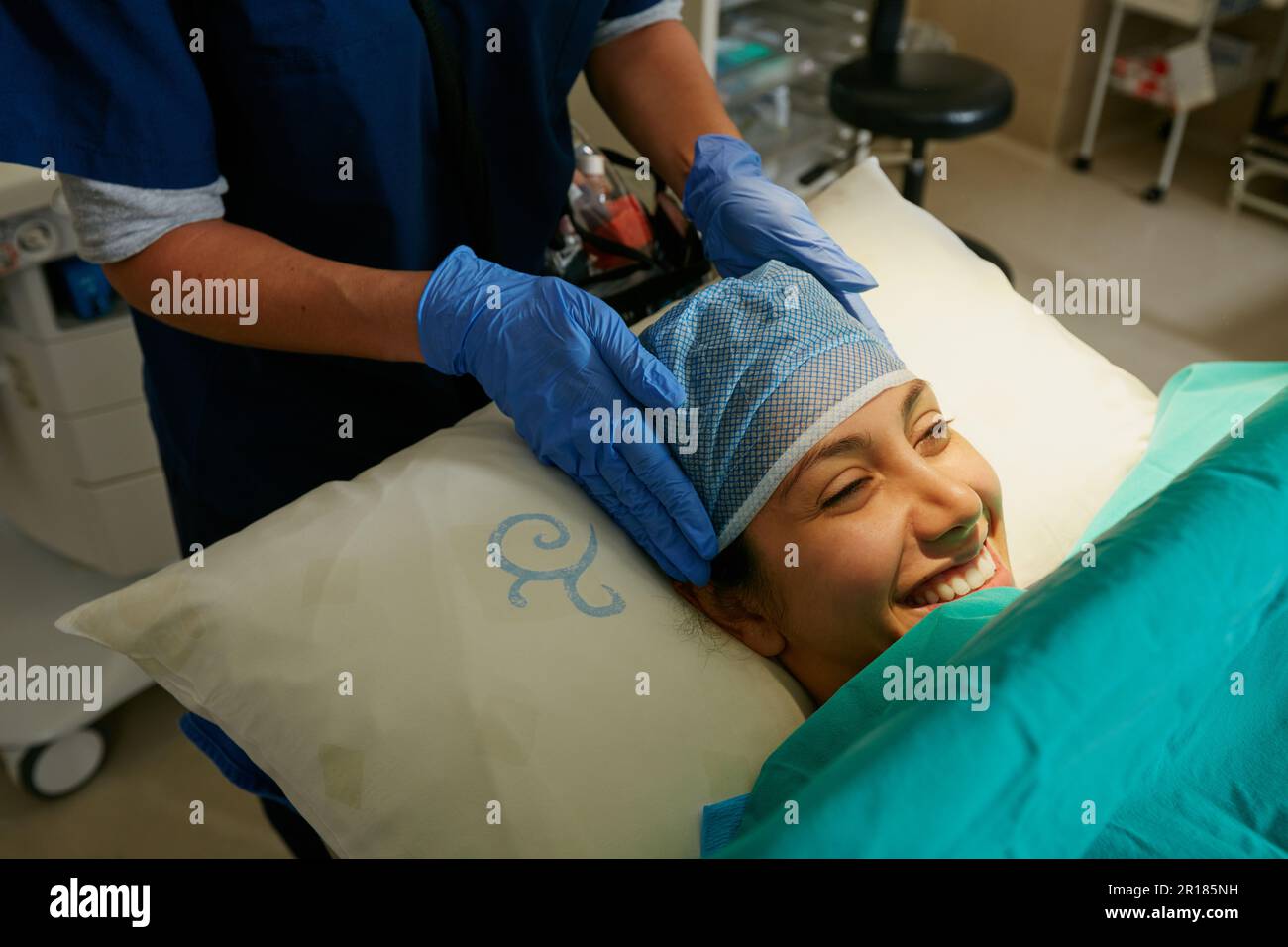 Vous êtes maintenant entre des mains sûres. une infirmière mettant une coiffe chirurgicale sur un patient en préparation de sa chirurgie. Banque D'Images