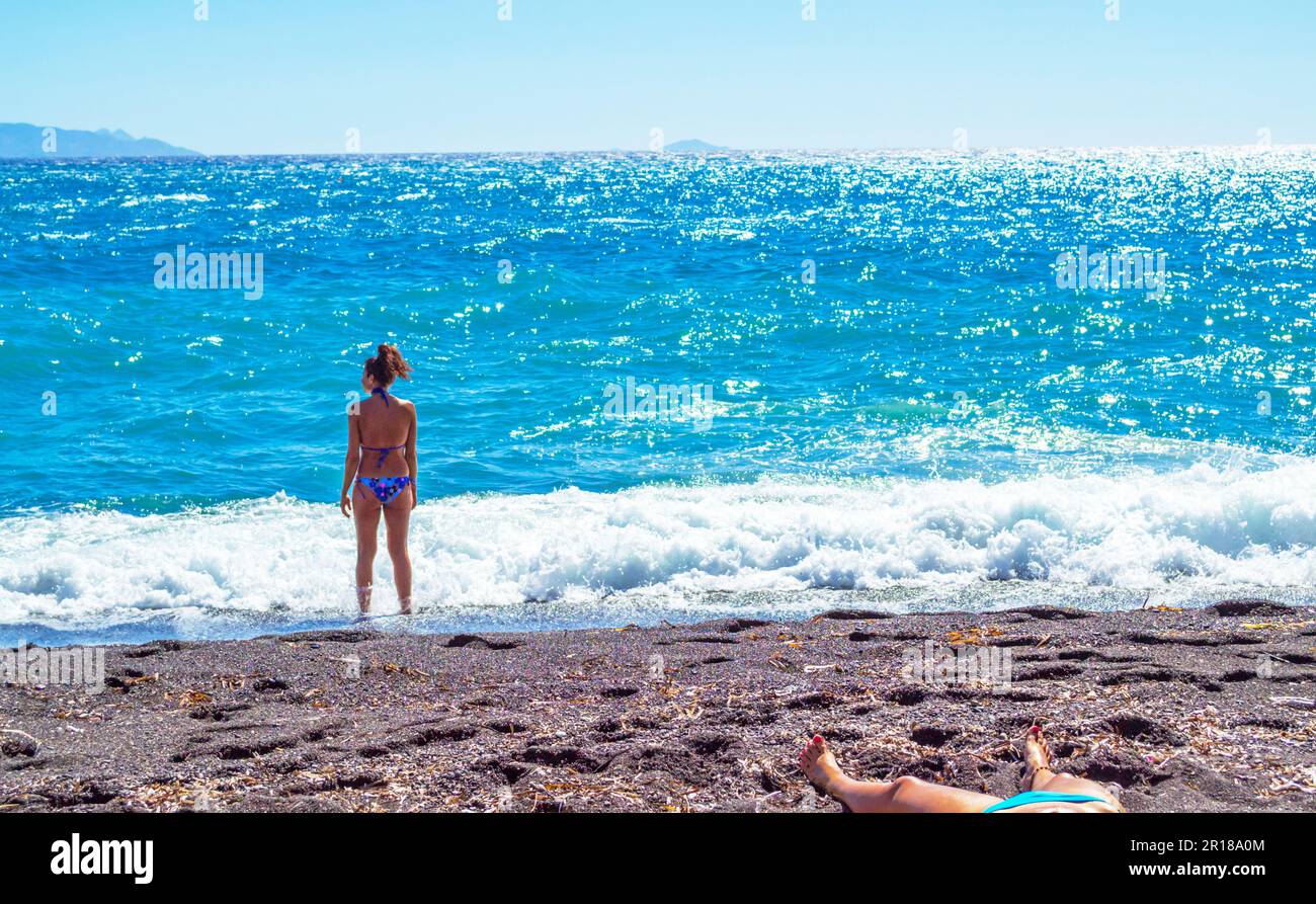 Bains de soleil femmes dans un maillot de bain sur la mer en appréciant l'incroyable mer Égée vista.photo prise à Kamari, Santorini, Grèce - unique, île étonnante Banque D'Images