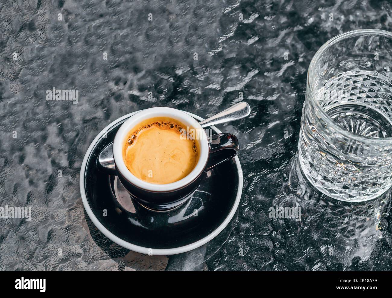 Tasse d'espresso en porcelaine noire sur la table avec un verre d'eau Banque D'Images